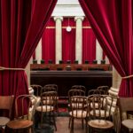 red curtain near brown wooden chairs